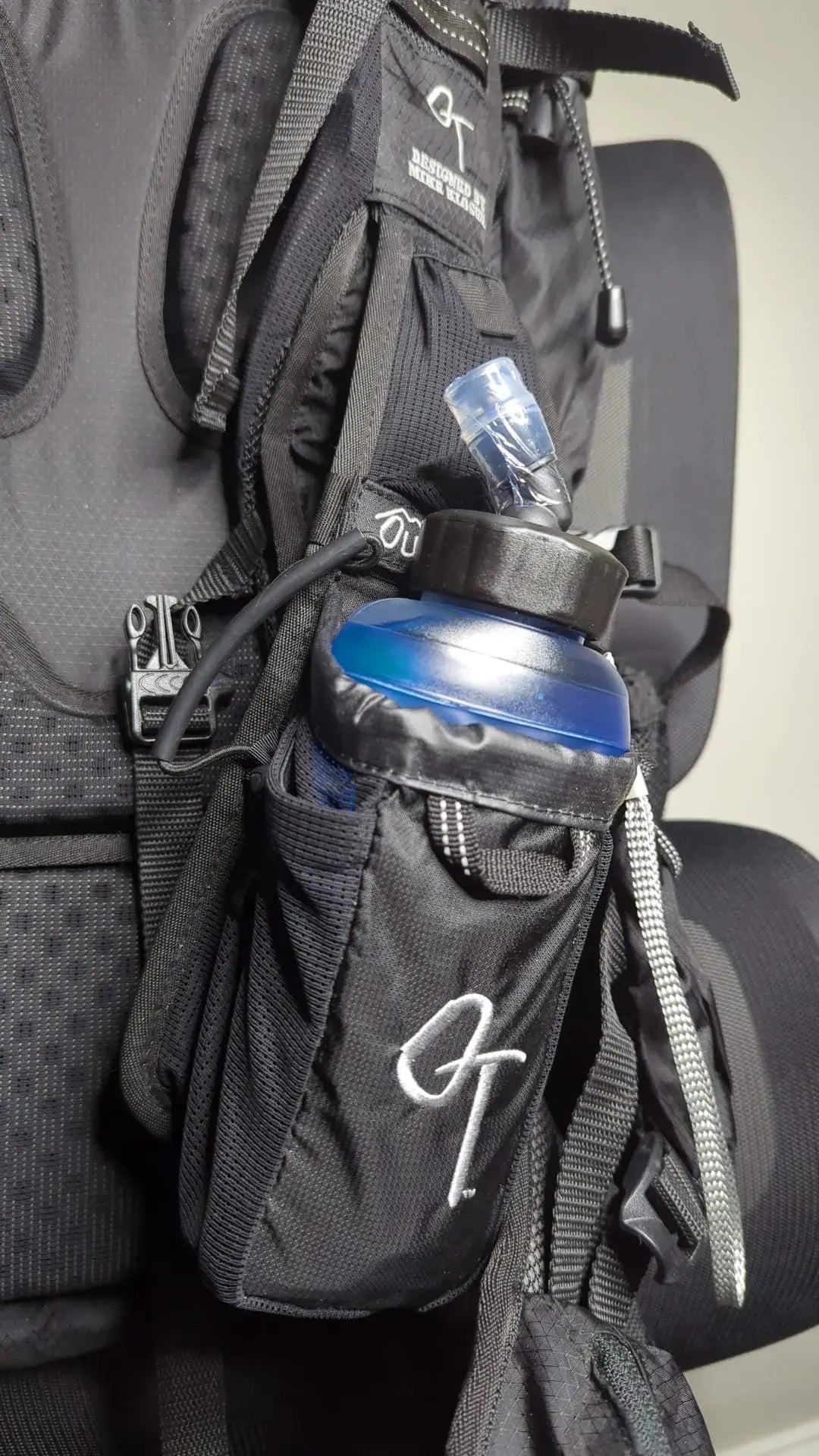 Black backpack with a water bottle holder attached, featuring a visible OutThere brand logo.