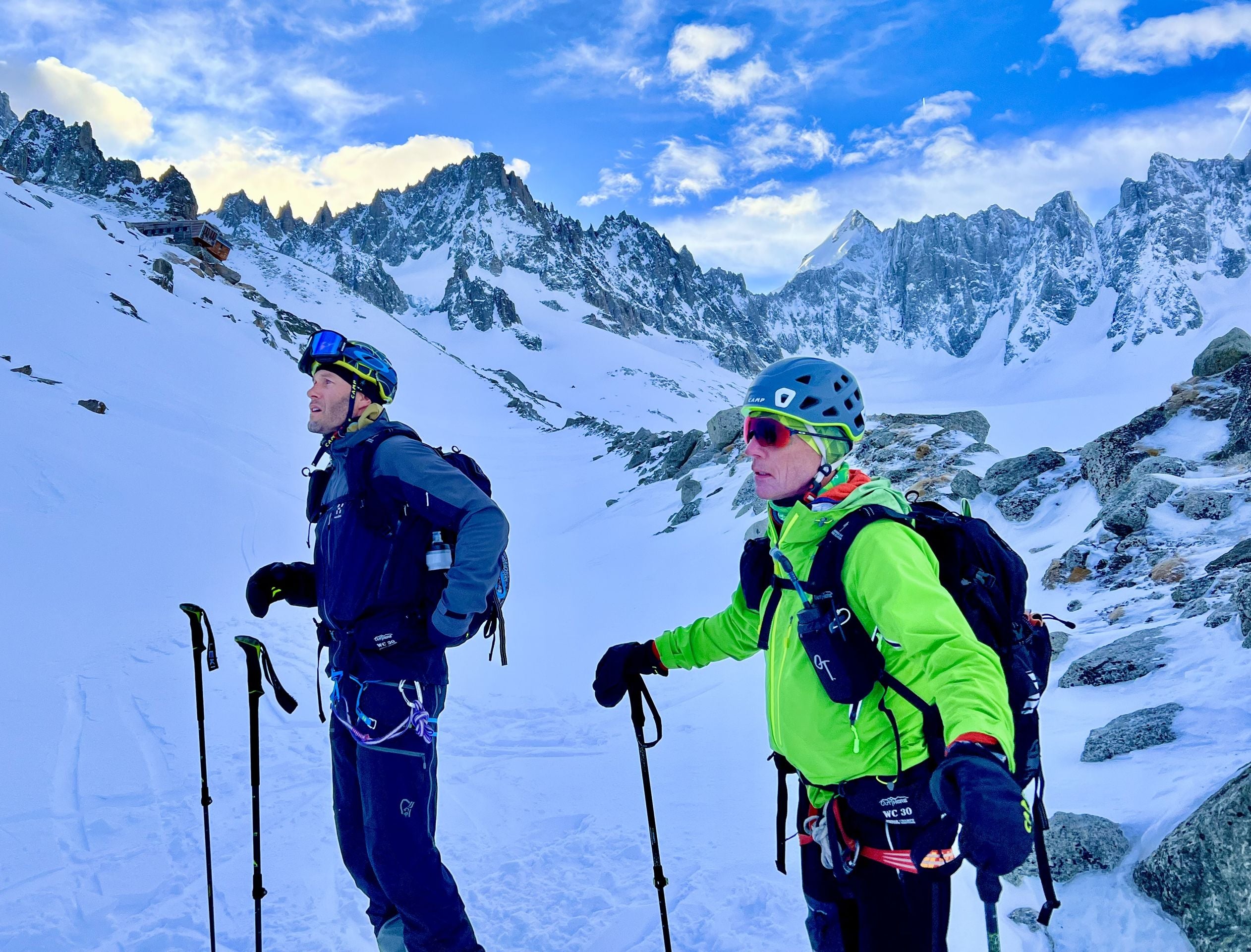 Two climbers on a snowy mountain with backpacks and climbing gear.